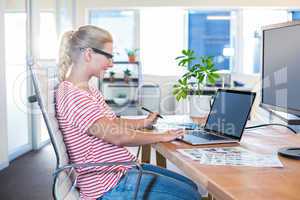 Cheerful casual businesswoman using laptop and digitizer