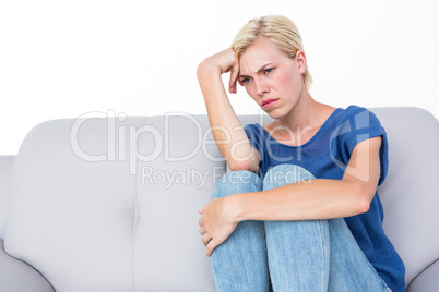 Thoughtful blonde woman sitting on the couch