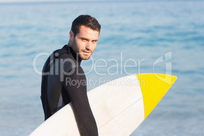 Man in wetsuit with a surfboard on a sunny day