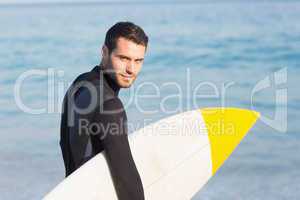 Man in wetsuit with a surfboard on a sunny day