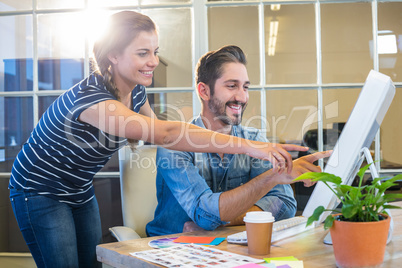 Smiling colleagues working together on computer