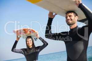 happy couple in wetsuits with surfboard on a sunny day