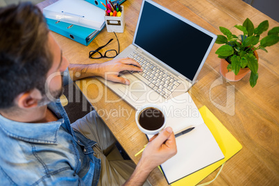 Casual businessman working at his desk and holding cup of coffee