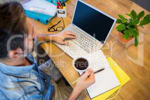 Casual businessman working at his desk and holding cup of coffee