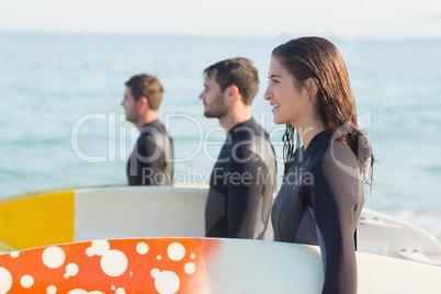 Group of friends on wetsuits with a surfboard on a sunny day