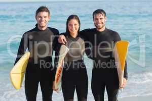 Group of friends on wetsuits with a surfboard on a sunny day