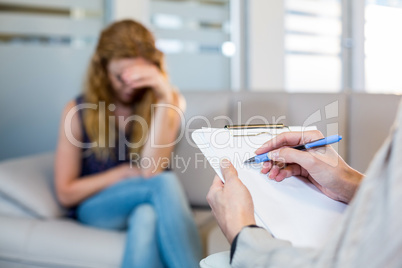 Psychologist talking with her depressed patient and taking notes