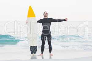 Man in wetsuit with a surfboard on a sunny day