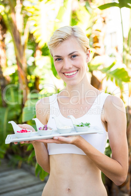 Happy blonde woman holding plate with herbal medicine