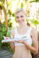 Happy blonde woman holding plate with herbal medicine