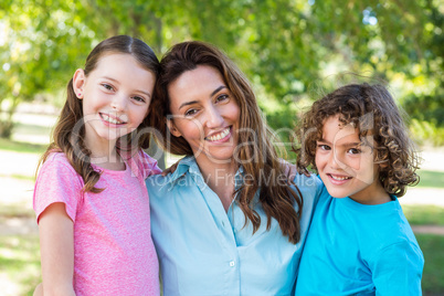 mother and children smiling and kissing in a park
