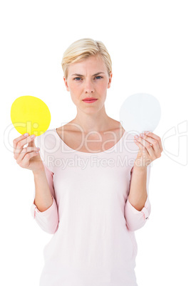 Serious blonde woman holding white and yellow sheets of paper