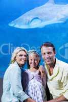 Happy family looking at camera beside the fish tank