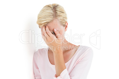 Nervous blonde woman covering her face
