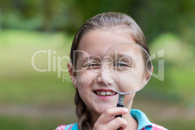 Curious little girl looking through magnifying glass