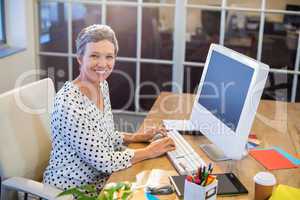 Smiling businesswoman typing on keyboard