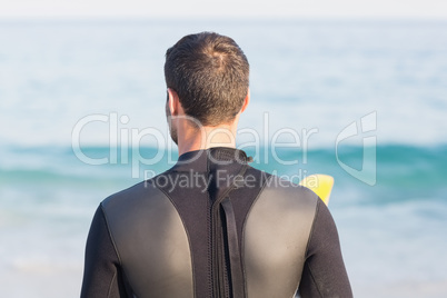 Man in wetsuit with a surfboard on a sunny day