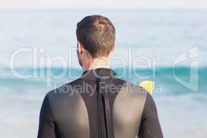 Man in wetsuit with a surfboard on a sunny day