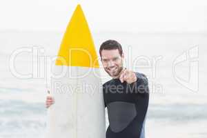 Man in wetsuit with a surfboard on a sunny day