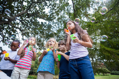 Little friends blowing bubbles in park