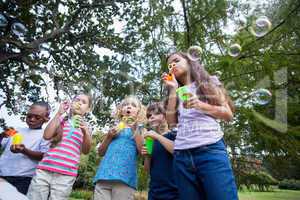 Little friends blowing bubbles in park