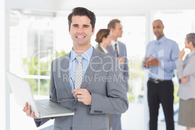 Businessman with his laptop and his colleagues behind