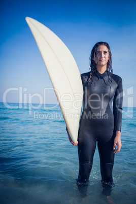 woman in wetsuit with a surfboard on a sunny day