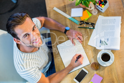 Smiling casual businessman writing in notepad