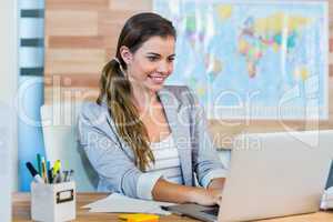 Pretty travel agent working on laptop