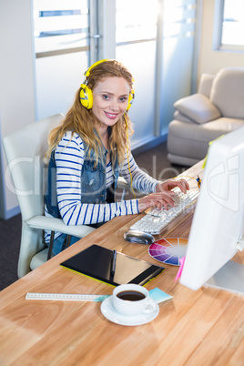 Smiling designer typing on keyboard and listening music