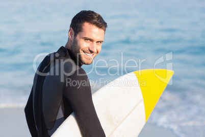 Man in wetsuit with a surfboard on a sunny day