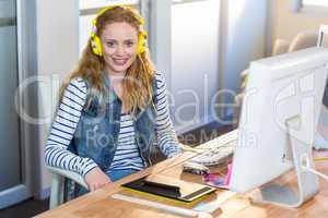 Smiling businesswoman sitting at her desk and listening music