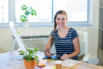 Smiling designer sitting at her desk and working with digitizer