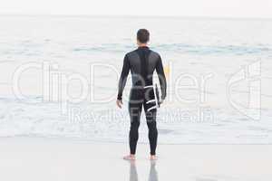 Man in wetsuit with a surfboard on a sunny day