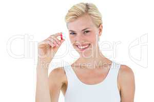 Smiling blonde woman looking at red pill