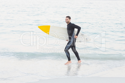 Man in wetsuit with a surfboard on a sunny day