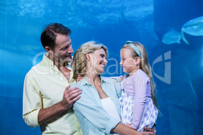 Happy family smiling at each other beside the fish tank