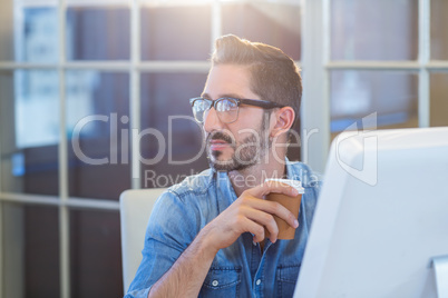 Casual businessman sitting at desk and holding coffee
