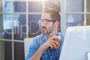 Casual businessman sitting at desk and holding coffee