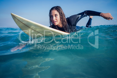 woman in wetsuit with a surfboard on a sunny day