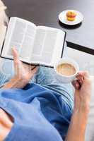Woman reading a book and holding cup of coffee