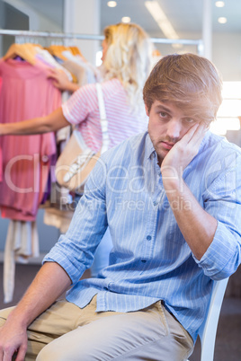 Happy blonde woman doing shopping with her exhausted boyfriend