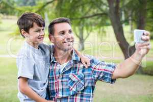 Father and son taking a selfie in the park