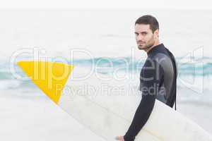 Man in wetsuit with a surfboard on a sunny day