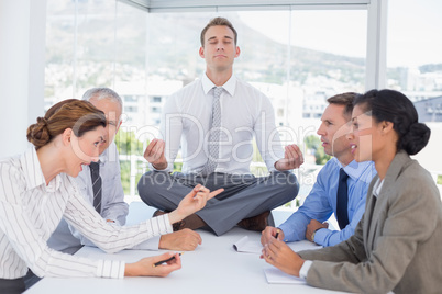 Businessman relaxing on the desk with upset colleagues around