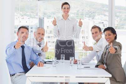 Business team smiling at camera showing thumbs up