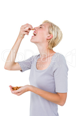 Happy blonde woman eating almond nuts