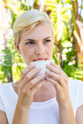 Attractive blonde woman drinking hot beverage