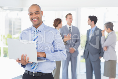 Businessman with his laptop and his colleagues behind