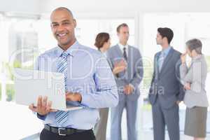 Businessman with his laptop and his colleagues behind